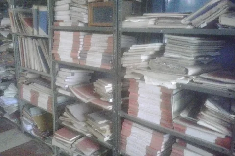 Files stacked on shelves in a government office (representative)