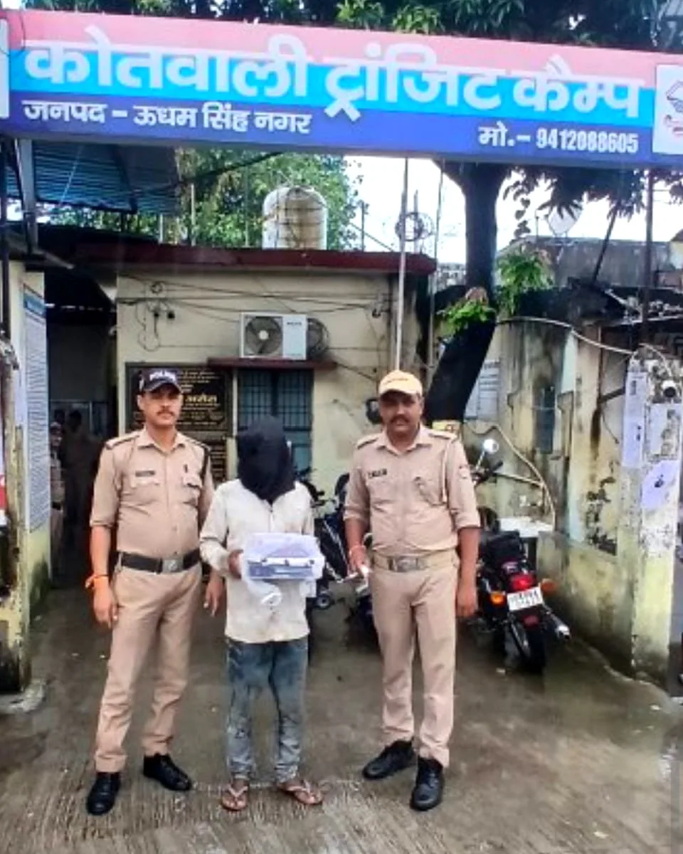 कोतवाली ट्रांजिट कैंप के बाहर दो पुलिसकर्मियों के बीच चेहरा ढके आरोपी, हाथ में बरामद मोबाइल फ़ोन