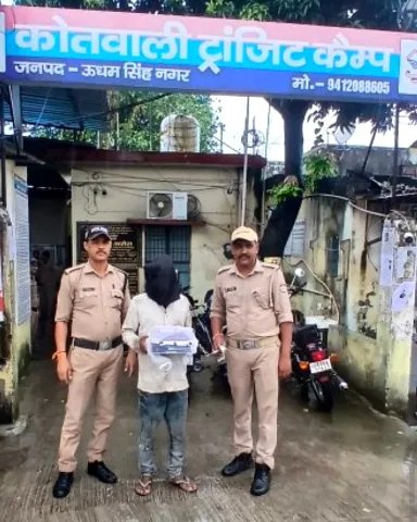 कोतवाली ट्रांजिट कैंप के बाहर दो पुलिसकर्मियों के बीच चेहरा ढके आरोपी, हाथ में बरामद मोबाइल फ़ोन